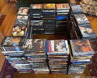 Five large stacks of DVD and Blu-ray cases arranged on the floor and surrounding area