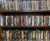 Three shelves filled with various DVDs and Blu-Rays, titles visible include "Saving General Yang," "The Sympathizer," "Submarine Warfare," and "Spartacus".