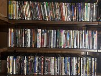 Wide shot of DVDs and Blu-Rays on two wooden shelves showing a large variety of titles and genres.