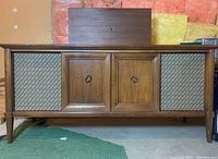 Front view of the wooden console stereo cabinet with speaker grills and closed wooden cabinet doors.