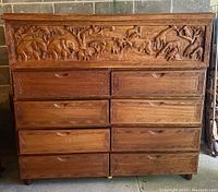 Front view of large wooden cabinet with 8 drawers and carved flip-top chest.