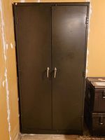 Front view of tall dark metal storage cabinet with two vertical doors closed.