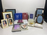 Photo showing multiple metal picture frames in various sizes and finishes arranged on a table, with some boxed sets, and inserts showing sample images.