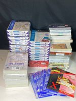 Photo showing organized stacks of multiple reams of letterhead and legal-size printer paper with visible brand and paper details, alongside envelopes and note pads, all packed in boxes for easy removal.