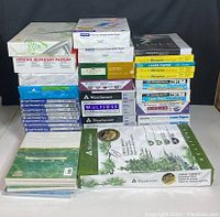 Photo showing stacked reams of assorted letter, legal, and 11x17 printing papers from multiple brands including Weyerhaeuser, Sphinx, Epson, and others.