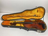 Violin with bow inside hard case with orange plush lining, showing overall condition and interior.