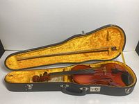 Suzuki 22 violin inside black hard case with yellow velvet interior, bow attached inside case lid.
