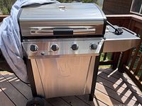 Full frontal view of the assembled Char-Broil grill on outdoor decking, showing control panel, wheels, and part of side burner with cover.