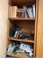 Photo of upper and middle shelves in wooden cabinet showing wooden blocks, sandpaper sheets, and some small hand tools