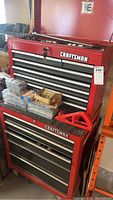 Stacked red Craftsman top and bottom tool chests with items on top