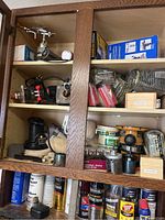 Cabinet shelves showing Dremel rotary tool accessories, router, router bits, abrasives and spray cans beneath.