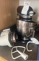 KitchenAid black stand mixer with stainless steel bowl attached, separate bowl and mixer attachments on countertop