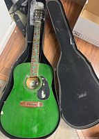 Full guitar in case, showing overall green body and fretboard with custom inlays.