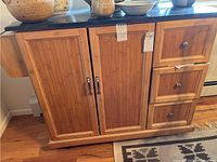 Front view of bamboo rolling island cabinet with granite top showing two central doors and three right-side drawers