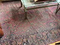 Overall view of rug under glass coffee table showing red floral medallion pattern