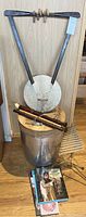 Photo showing the stringed instrument, metal percussion barrel, flutes, pan flute, drumsticks, and books