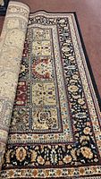 Area rug partially unrolled showing detailed pattern with multiple colors and floral motifs.