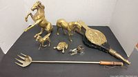 Overview photo showing all brass items including two horses, frog, turtle, bellows, candle snuffer, and long handled fork