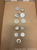 Ten coins arranged in rows on a cardboard surface showing various Canadian, US, and English coins.