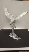 Front and side views of heavy cast metal eagle sculpture showing detailed feathers and outstretched wings on textured stand.