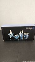 Box front showing image of four miniature Thierry Mugler Angel perfume bottles in blue glass shapes.
