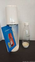 Full view of SodaStream appliance with carbonating bottle and user manual