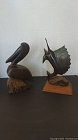 Pelican and sailfish wood carvings side by side showing scale and design details