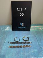 Four assorted vintage bracelets including two cuff bangles and two chain-link bracelets arranged on a blue cloth.