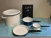 Full view of the enamel cookware set showing all four items on a blue surface with beige background.