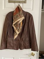 Brown faux leather jacket hanging with Italian brown and taupe paisley scarf on hanger