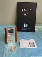 Ultronic MF7 remote clock radio with manual and bubble wrap package displayed on table with lot sign in background.