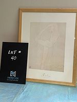Framed Rodin print held against a pale wall next to a black sign with white text reading 'Lot #40'. Image shows the entire frame and the print centrally positioned within it.