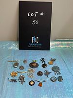 All 21 brooches arranged on holographic blue surface with lot sign