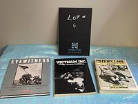 Three vintage coffee table books laid flat on a table with a black sign 'Lot #6' behind.