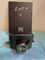 Front view of the Petri 7 camera inside its closed dark green leather carrying case with Petri logo on lens cap.