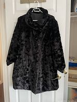 Black plush fur-like side of the reversible coat with button closure and collar visible.