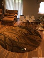 Full view of the round wool area rug on hardwood floor under natural light, showing its size and color pattern.