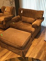 View of brown oversized upholstered armchair with matching ottoman in front, displaying overall condition and color.