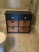 Full view of chest with top painted drawers and straw weave baskets below in a bathroom setting.