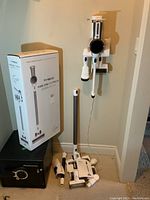 Full view of vacuum, attachments, wall bracket and original box alongside safe