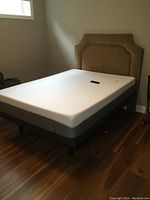 Full view of the bed with upholstered headboard, mattress and frame