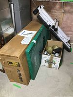 BodyFlux folding weight bench folded and leaning against wall with box of mixed dumbbell weights and green exercise mat next to it