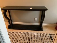 Front view of hall table showing dark ebony finish and curved leg supports with lower shelf.