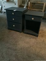 Two dark painted wood nightstands positioned side by side on carpeted floor, one with three drawers and one with one drawer plus open space below.