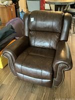 Front view of brown faux leather rocker recliner showing overall shape and upholstery condition