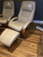 Front view of beige leather swivel recliner and matching ottoman on wooden floor