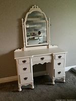 Full front view of the white painted wood vanity with attached swivel mirror showing its size and styling.