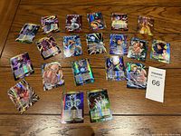 Full view of 20 Dragon Ball collectable cards arranged on a wooden surface showing diverse characters and holographic effects.