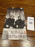 Cover of Simon & Garfunkel Old Friends booklet showing black and white photo of duo sitting by microphones looking to the side.