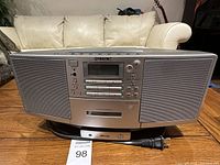 Front view of Sony ZS-D5 unit showing dual speakers, control panel, cassette deck, and power cord.